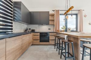 kuchnia z drewnianymi szafkami i bar z stołkami w obiekcie Przepiękny apartament ORANGE z widokiem na Skrzyczne - Sun&Sport w Szczyrku