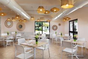 a dining room with tables and chairs and chandeliers at VOI Le Muse Essentia in Zambrone