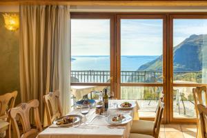 comedor con mesa y ventana grande en Hotel Residence Panorama La Forca, GTSGroup, en Tignale