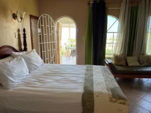 ein Schlafzimmer mit einem großen weißen Bett und einer Couch in der Unterkunft Kris’o Super Studio in Ocho Rios