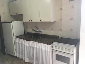 Una cocina con fregadero y refrigerador blanco. en Campos do Jordão, en Campos do Jordão