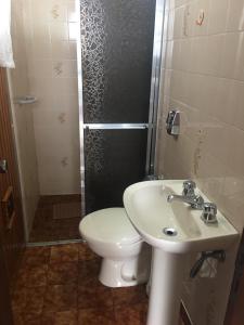 Un baño con inodoro, lavabo y ducha. en Campos do Jordão, en Campos do Jordão