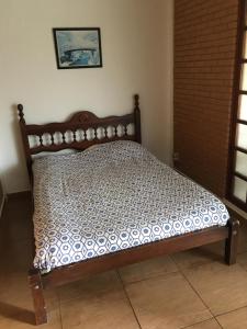 1 cama con marco de madera en una habitación en Campos do Jordão, en Campos do Jordão