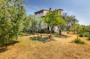 a house in a garden with trees and a swing at Apartment Luana A2 in Fažana