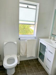 a white bathroom with a toilet and a window at Esplanade Bliss in Cronulla