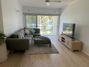 a living room with a couch and a flat screen tv at Esplanade Bliss in Cronulla