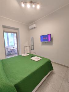 a bedroom with a green bed with a tv on the wall at Apartment NAPOLI MARADONA in Naples