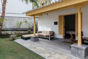 a house with a patio with a couch and a television at Dots Bay House in Hiriketiya