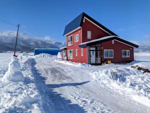 富良野市にあるAll Seasons Furano Chaletの雪だるまが赤い家の隣に立っている