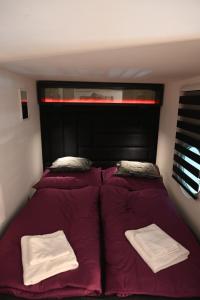 a bed with purple sheets and two white towels on it at Akacfaapartman in Budapest