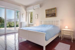een witte slaapkamer met een bed en een raam bij Villa Belvedere-Con piscina a Bardolino in Costermano
