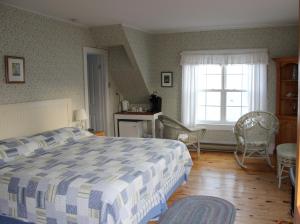 1 dormitorio con 1 cama, ventana y sillas en Compass Rose Heritage Inn, en North Head