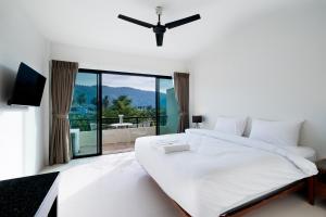 a white bedroom with a large bed and a balcony at Hill Myna Holiday Park & Cafe in Bang Tao Beach