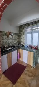 uma cozinha com armários brancos e uma parede de tijolos em Blue Valley Apartment em Darjeeling