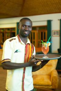 a man holding a tray with a drink on it at Gorilla Leisure Lodge in Kisoro