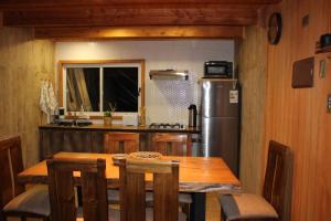 Casa Loft Küme Felen في بوكون: مطبخ مع طاولة خشبية وثلاجة