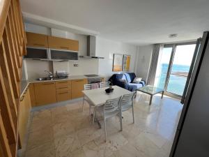 a kitchen and a living room with a table and chairs at Pearl Apartment Corralejo in Corralejo
