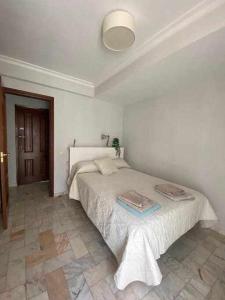 a white bedroom with a bed in a room at acogedor apartamento placentines in Seville