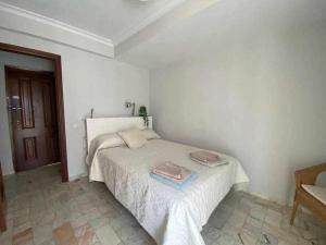 a white bedroom with a bed with two towels on it at acogedor apartamento placentines in Seville
