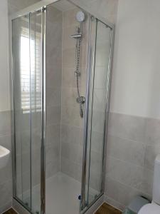 baño con cabina de ducha con puerta de cristal en Remarkable and modern house in Rugby England en Rugby