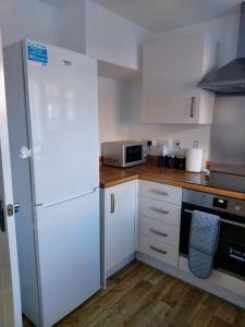 eine Küche mit einem weißen Kühlschrank und einer Mikrowelle in der Unterkunft Remarkable and modern house in Rugby England in Rugby