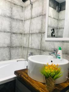 ein Badezimmer mit einem weißen Waschbecken und einem Spiegel in der Unterkunft Квартира в стиле лофт in Qaraghandy