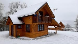 une cabane en rondins avec de la neige sur le toit dans l'établissement Domek Pod Smrekiem, à Marcinkowice