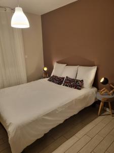 1 dormitorio con 1 cama blanca y 2 almohadas en Au cocon de Lin, en Le Neubourg