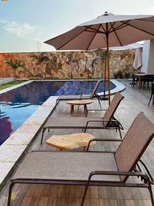 uma piscina com cadeiras, um guarda-sol e uma mesa em Apartamento Paz e Traquilidade na praia em Luís Correia