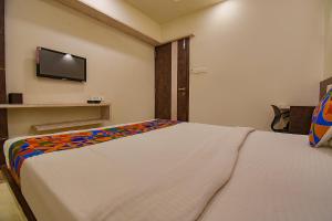 1 dormitorio con 1 cama y TV en la pared en FabHotel Royce Studio Apartments en Pune