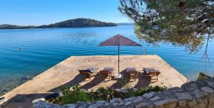 einen Tisch und Stühle mit einem Regenschirm auf einer Anlegestelle im Wasser in der Unterkunft Hidden Pearl in Luka