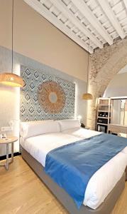 a bedroom with a large bed with a blue blanket at Soho Boutique Cádiz in Cádiz