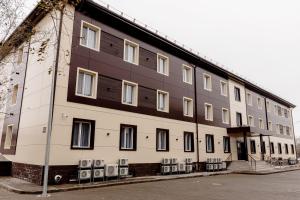 a large white building with several windows and chairs at Chagala Hotel Aksai in Aksay