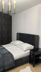 a bedroom with a bed with a black headboard and a table at Apartament Złoty 4 in Zblewo