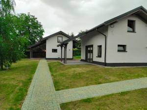 een wit huis met een grasveld ervoor bij Domki Pod Brzozami Ustroń 2 in Ustroń