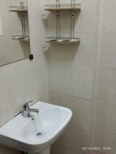 a bathroom with a sink and shelves on the wall at Al Basateen Hotel Apartment in Sur