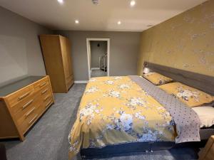 a bedroom with a large bed and a dresser at Eden Vale Garden View Apartment with Patio in Morecambe