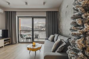 Szczyrk Ptasie Apartamenty NOWOŚĆ z widokiem na góry في شتوروك: غرفة معيشة مع أريكة وشجرة عيد الميلاد