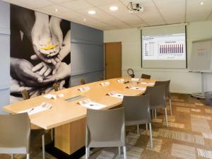 a meeting room with tables and chairs and a projection screen at Ibis Nantes la Beaujoire Parc Expo in Nantes