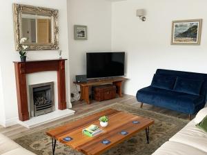 a living room with a blue couch and a fireplace at Sea Fern Luxury Cottage Fylingthorpe in Fylingthorpe