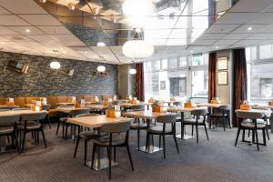een restaurant met tafels en stoelen en een muur van ramen bij Scandic Byparken in Bergen