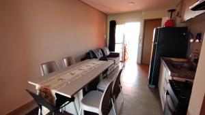 uma cozinha com uma mesa longa com cadeiras e um frigorífico em Apartamento Sossego em Luís Correia