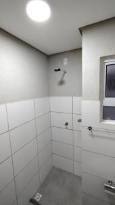 uma casa de banho com paredes em azulejos brancos e uma janela em Apartamento Sossego em Luís Correia