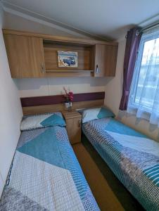 two beds in a small room with a window at Caravan Littlesea Haven Weymouth Amazing Views in Weymouth