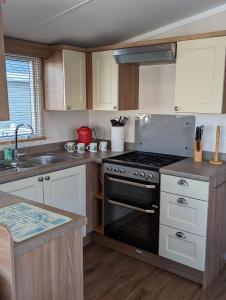 a kitchen with a stove and a sink at Caravan Littlesea Haven Weymouth Amazing Views in Weymouth