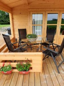une terrasse couverte avec une table, des chaises et des plantes dans l'établissement Prive jacuzzi cows dairyfarm relaxing sleeping, à Hitzum