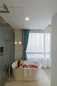 a bathroom with a tub with red petals on the floor at Odin Hotel Quy Nhon in Quy Nhon