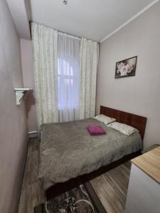 Habitación pequeña con cama y ventana en Оазис en Almaty