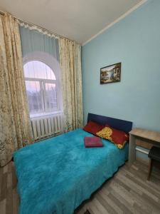Un dormitorio con una cama azul y una ventana en Оазис, en Almaty