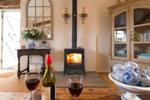 a living room with a fireplace and two glasses of wine at The Stables, relax in 5 star style and comfort with lovely walks all around in Great Maplestead